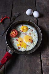 Fresh fried eggs in a frying pan on a wooden background. Top view.