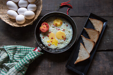 Breakfast item fried eggs in a frying pan on a background. Top view, selective focus.