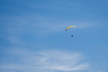 A paraglider with a motor flies in a blue cloudy sky. copyspace.