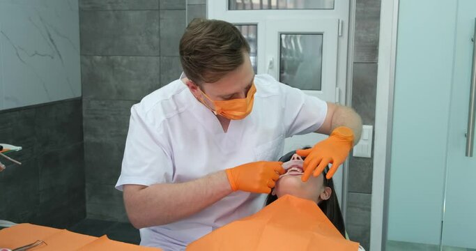 dentistry, stomatologist professionally installs dental expander in mouth of female patient before starting cleaning teeth and treatment then lowers chair to complete medical procedure in clinic