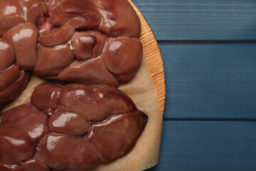 Fresh raw kidney meat on blue wooden table, top view. Space for text