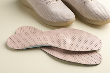 Beige orthopedic insoles and shoes on beige background