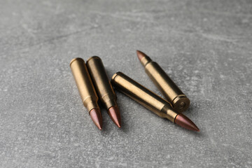 Bullets on light grey table, closeup. Firearm ammunition