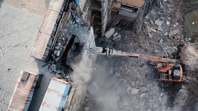 Aerial View Excavators Dismantle The Concrete Structures Of The Building. Hydraulic machinery working to get rid of the rubbish in a demolition site.