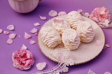 Natural homemade vanilla sugar free marshmallows with cup of coffee. Healthy sweets, natural food. Romantic purple background with tea rose decorations.
