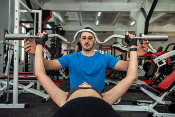 Fototapeta na wymiar personal male trainer working with young slim woman client in gym