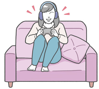 Young Asian woman sitting on a sofa wearing headphones, enjoying a video game alone