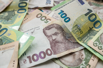 Obraz na płótnie Canvas Top view of various euro and Ukrainian hryvnia banknotes on a spacious table.