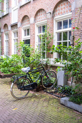 Fototapeta na wymiar Bicycle parked in front of a red brick building, Amsterdam city neighborhood. Holland Netherlands.