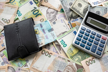 many euro hryvnia banknotes lie on the table next to a wallet with money and a calculator table