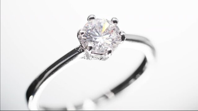 Engagement diamond ring rotating on black background. Traditional piece of jewelry, macro shot.
