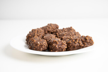 Chocolate candy bars lie on a white plate on a white background