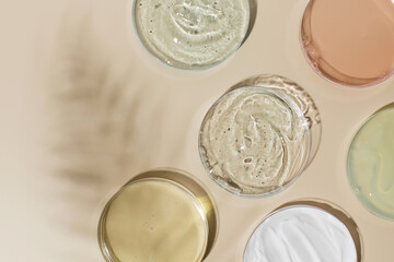 Different skincare products in Petri dishes and shadow on yellow background. Flat lay