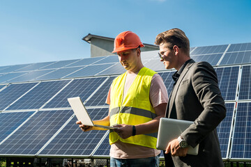 near  solar panels, the employee shows the work plan to the boss