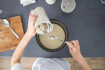 Woman pouring dough into baking dish. Top view, flat lay