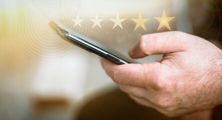 Close-up image of man hand using mobile smart phone with icon five star symbol to increase rating of company.