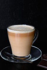 Coffee in glass cup and chocolate on a dark background