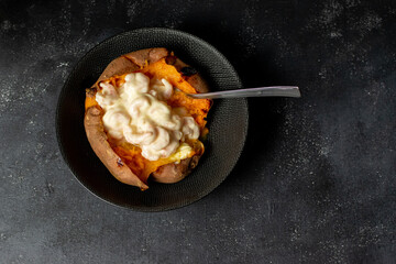baked whole sweet potato with prawn mayonnaise filling on a black background 