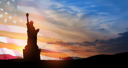 Statue of Liberty with a large american flag and sunset sky on background. Greeting card for...