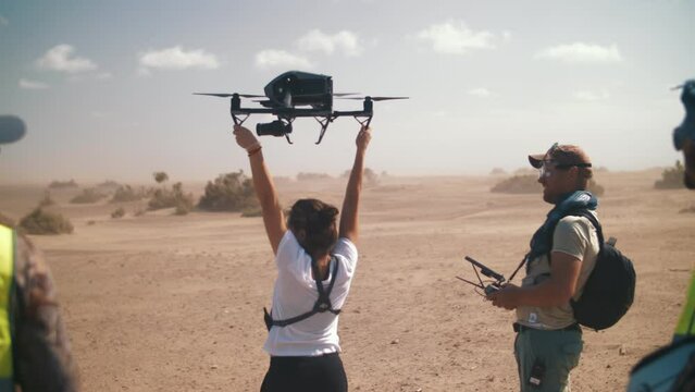 A girl catches a quadcopter with a camera in the air on the set of a movie. Drone with a camera. Filming in the desert.