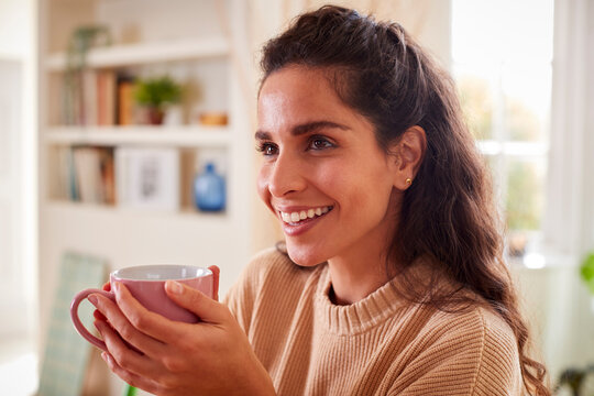 Woman Relaxing At Home Sitting At Table With Hot Drink