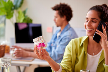Couple Running Online Business Making Boutique Candles At Home Talking On Mobile Phone