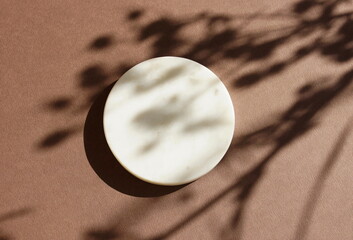 Marble white round podium and floral shadow on beige background. Place, background for cosmetics...