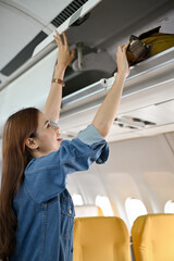 Beautiful young asian woman putting her bag at overhead locker or overhead compartment.