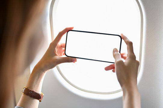 A female tourist using a mobile phone to take a sky picture outside of the plane. closeup