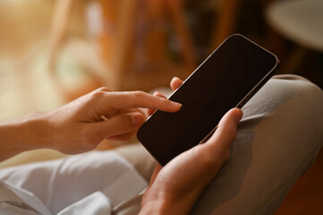 Male sitting on the chair and using smartphone. Phone black screen mockup. closeup