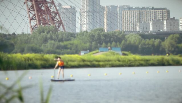 Unknown boy rides a SUP. Summer activities in big city, slow motion