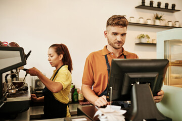 Coffeeshop owner working at cashier desk when b as tostada making coffee