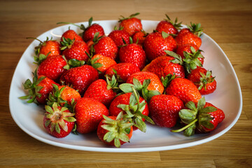 Strawberries on plate, wooden table