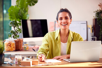 Portrait Of Woman Running Online Business Making Boutique Candles At Home Working On Laptop