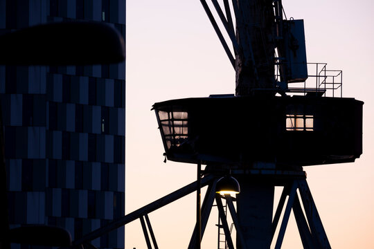 A silhouette of an old shipyard crane against the sunset