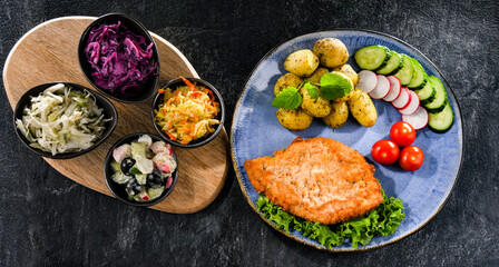 Pork cutlet coated with breadcrumbs with potatoes and salads