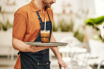 Waiter carrying tray with refreshing iced coffee to customer