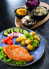 Pork cutlet coated with breadcrumbs with potatoes and salads