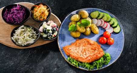 Pork cutlet coated with breadcrumbs with potatoes and salads