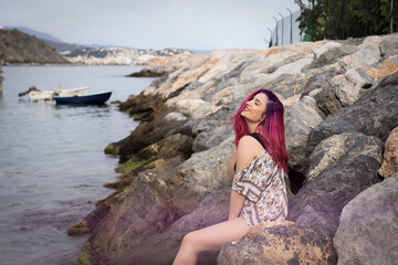 Young woman sitting on rocky seashore