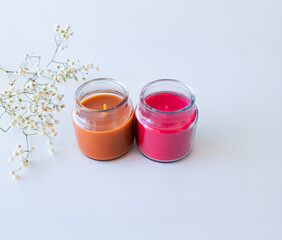 orange and red candles and white flowers on white background
