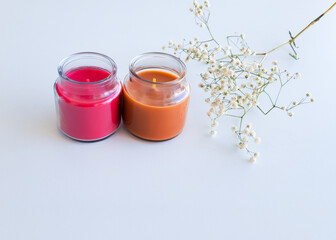 orange and red candles and white flowers on white background
