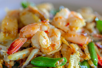 chopped raw vegetables in a frying pan with grilled shrimp