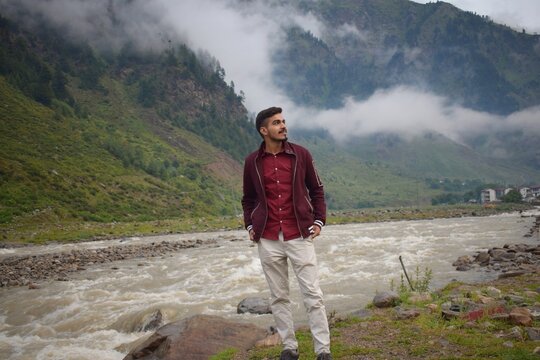 A young man in joyful and happy mood standing near bank of kunhar river in naran valley, kpk, pakistan.	
