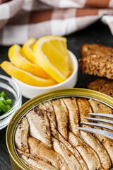 canned sprats in oil on a dark stone background