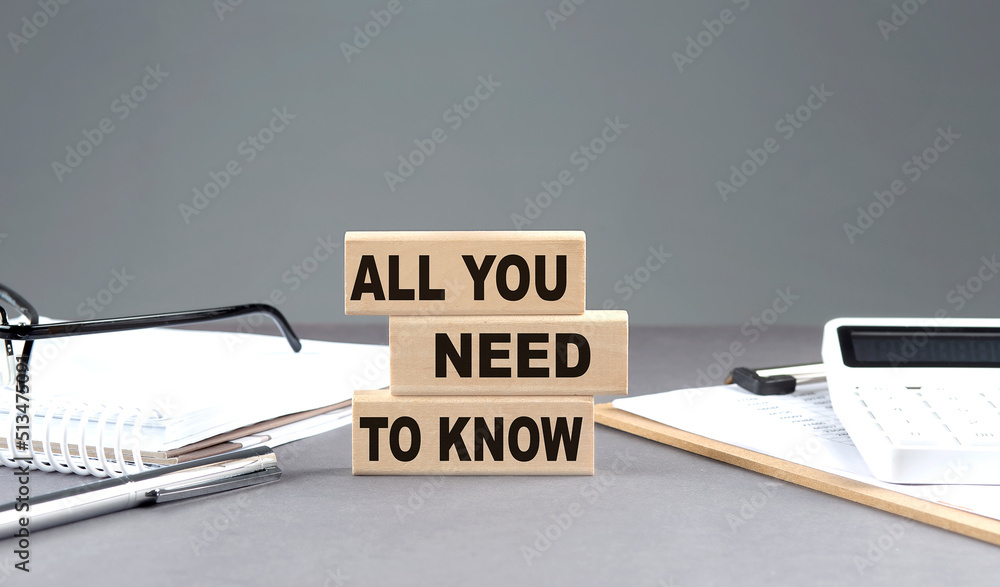 Poster all you need to know text on wooden block with notebook,chart and calculator, grey background