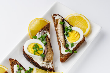 canapes with sprats on a white rustic wooden background