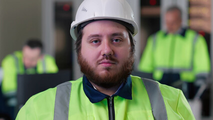 Portrait of overweight make engineer wearing safety vest and hardhat looking at camera