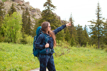 young female traveler with a backpack looks at the mountains. Hiking is an active lifestyle of people wearing a backpack, exercising outdoors. Selective focus