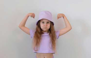 Baby cute girl shows strength and biceps. The concept of rules for girls. Tips for raising girls. The concept of the lifestyle of people with sincere emotions. To raise strong children